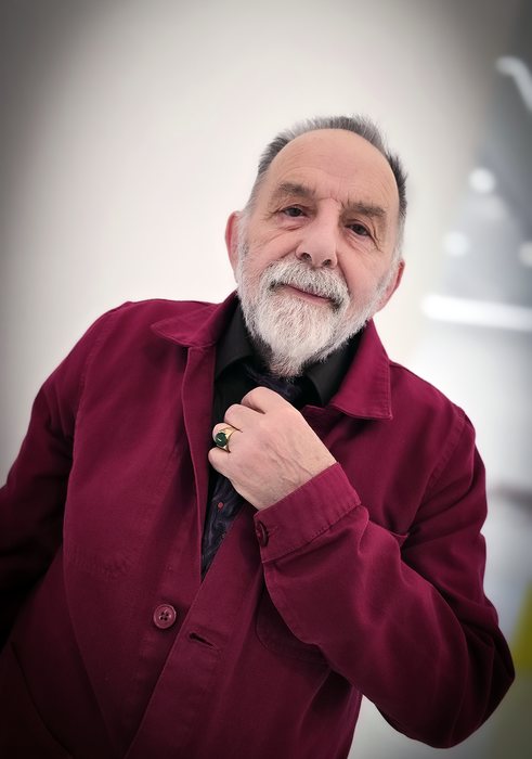 Portrait de Noël Dolla, en veste rouge, dans son atelier